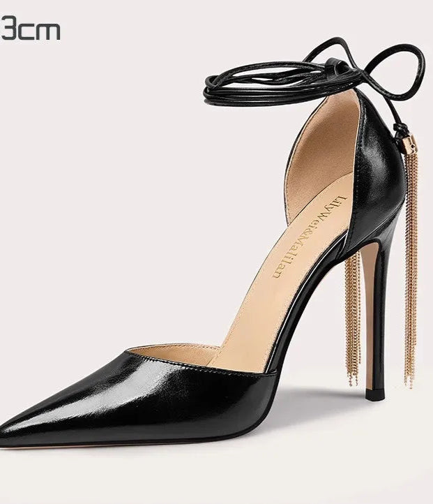 Black high-heeled shoe with a gold chain on a light gray background