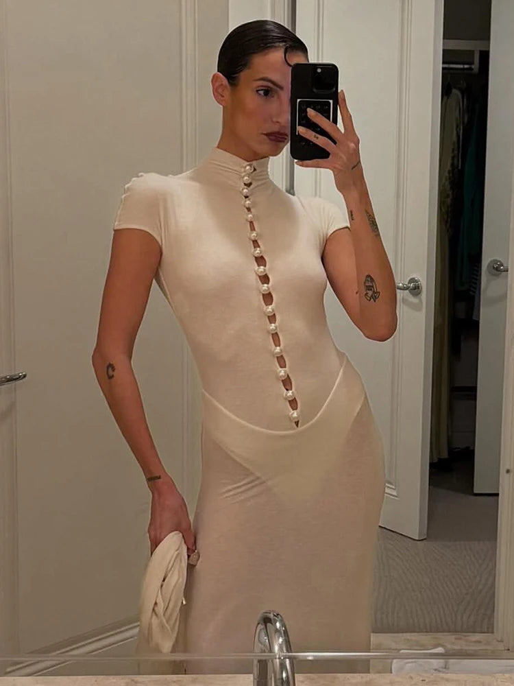 Woman taking a mirror selfie wearing a beige dress with pearl-like buttons.