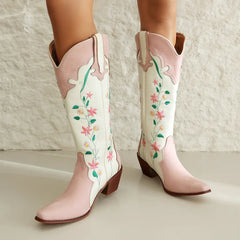 Pink and white cowboy boots with floral embroidery on a neutral background
