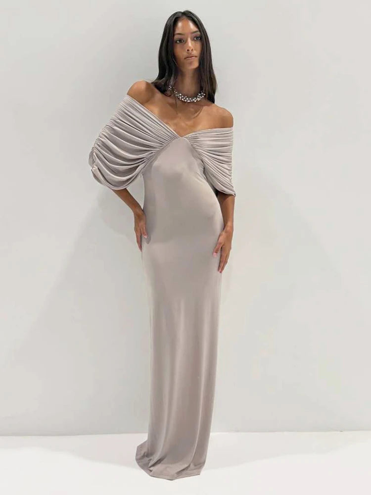 Full length view of a woman in a ruched off-shoulder maxi dress.