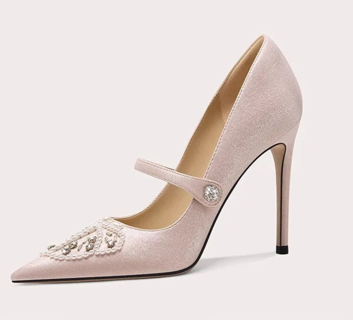 Pink high-heeled shoe with decorative strap on a light gray background