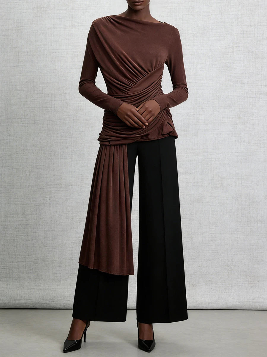 Person wearing a brown top and black pants against a gray background