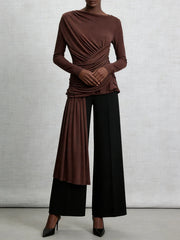 Person wearing a brown top and black pants against a gray background
