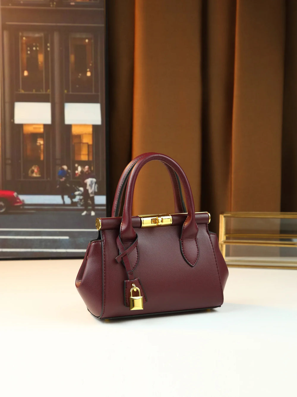 Structured leather top-handle bag with gold hardware and chain strap, front view