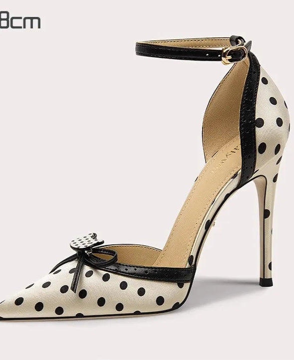 Polka dot high-heeled shoe with an ankle strap on a light gray background