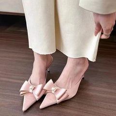  A woman wearing a pair of elegant beige bowknot kitten heels with pointed toes, perfect for formal events. 3