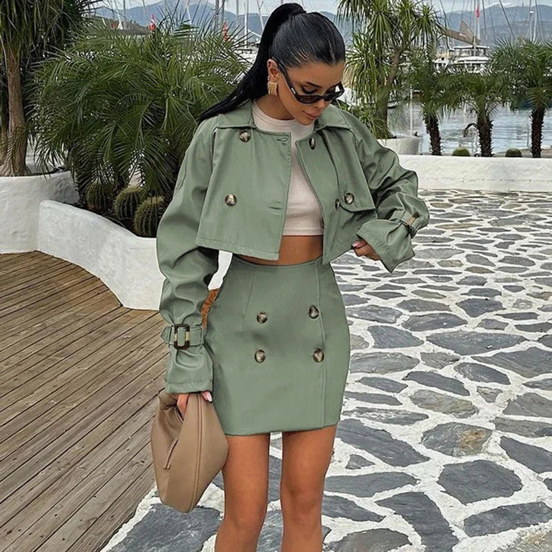 Woman in a green outfit standing on a stone pathway with a waterfront background