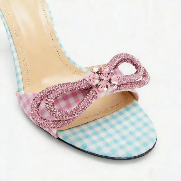 High-heeled sandal with pink bow and checkered sole on a white background