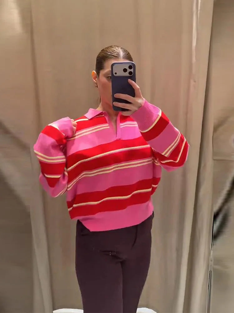 Person wearing a pink and red striped sweater taking a mirror selfie.