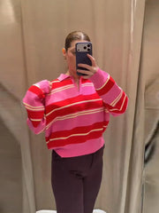 Person wearing a pink and red striped sweater taking a mirror selfie.