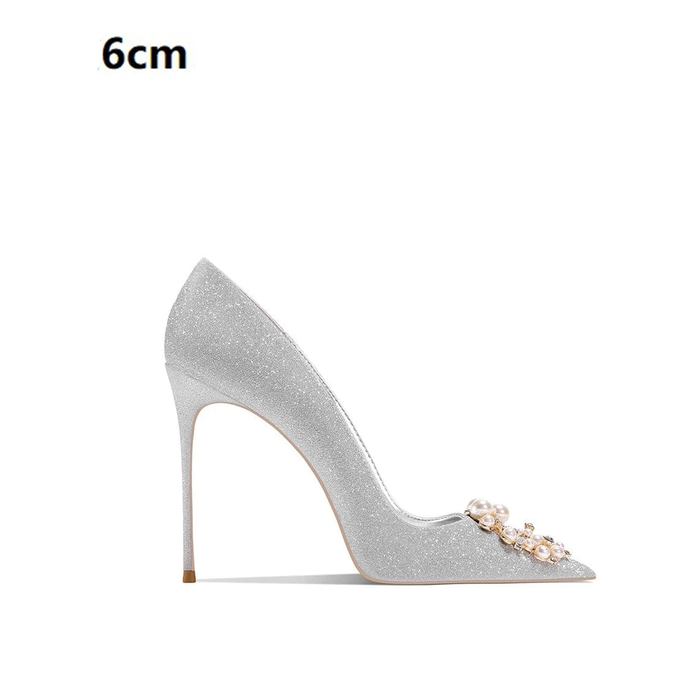 Silver high-heeled shoe with pearl embellishments on a white background