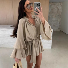 Woman taking a mirror selfie wearing a beige dress in a minimalistic room.