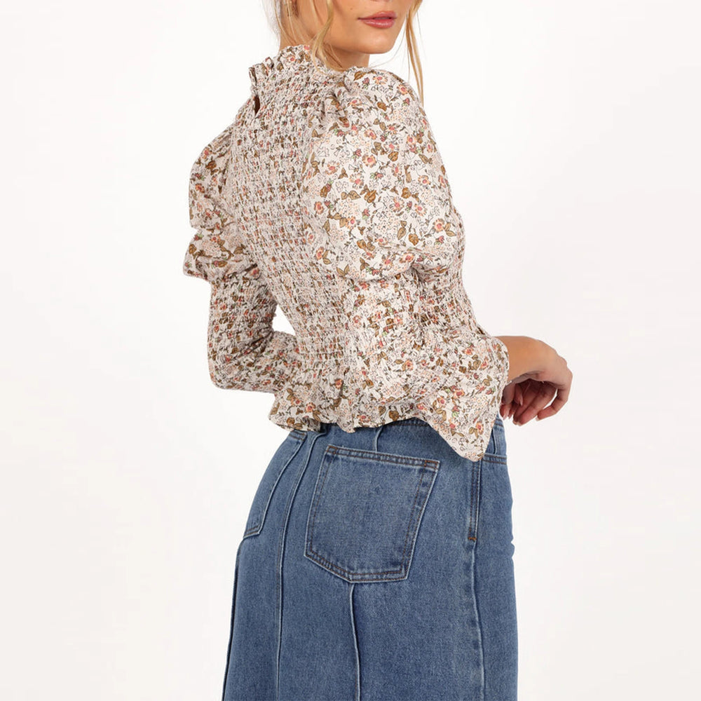 Woman wearing a floral blouse and blue jeans on a white background