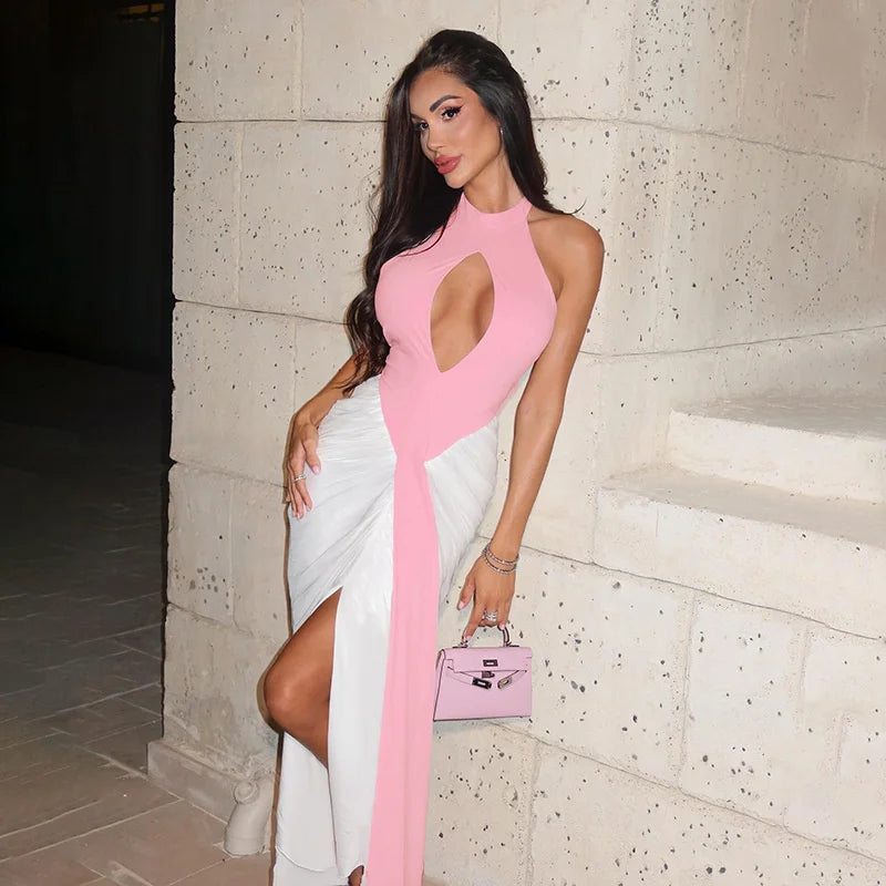 Woman in a pink and white dress standing against a textured wall.
