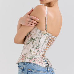 Woman wearing a floral lace top and jeans on a light gray background