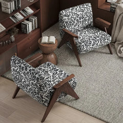 Two patterned armchairs in a room with a bookshelf and small table.