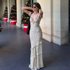 Woman in a floral dress standing outdoors with decorative Christmas trees in the background.