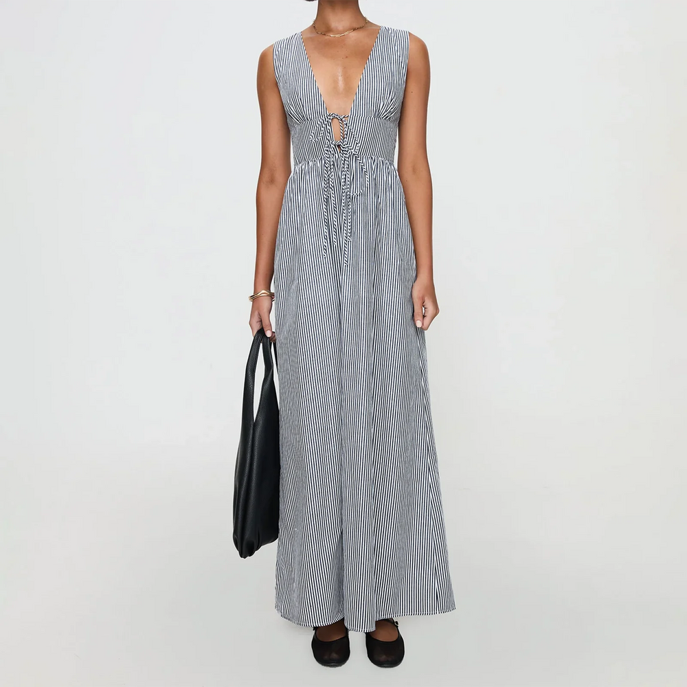 Woman wearing a long blue and white striped dress on a plain background