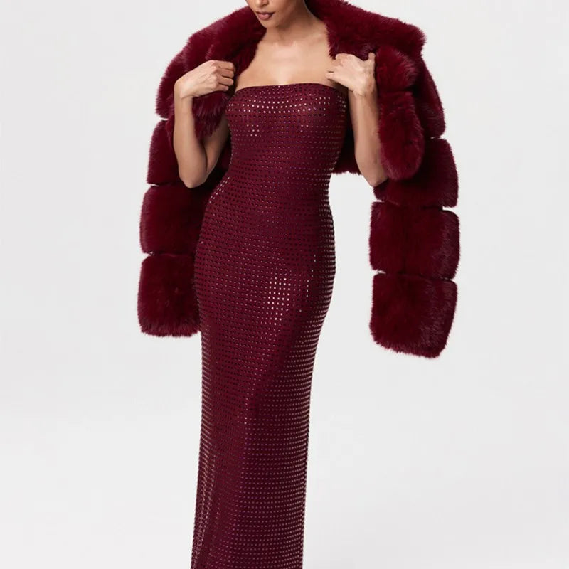 Woman wearing a burgundy strapless dress with a matching fur coat on a white background