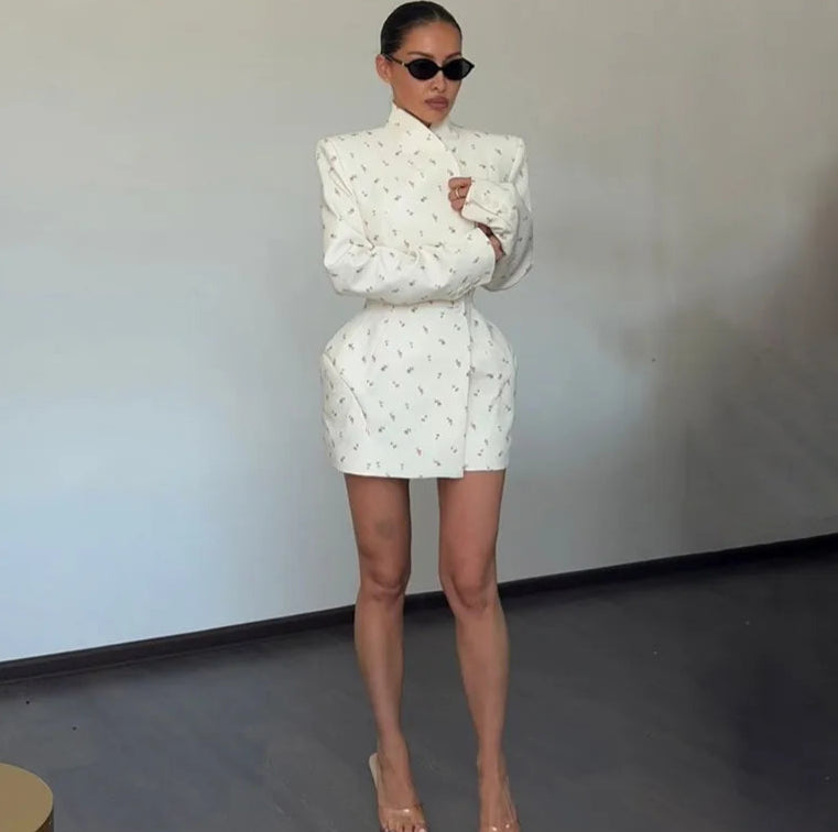 Person wearing a white outfit with puffed sleeves and a skirt, holding a pillow against a plain background.