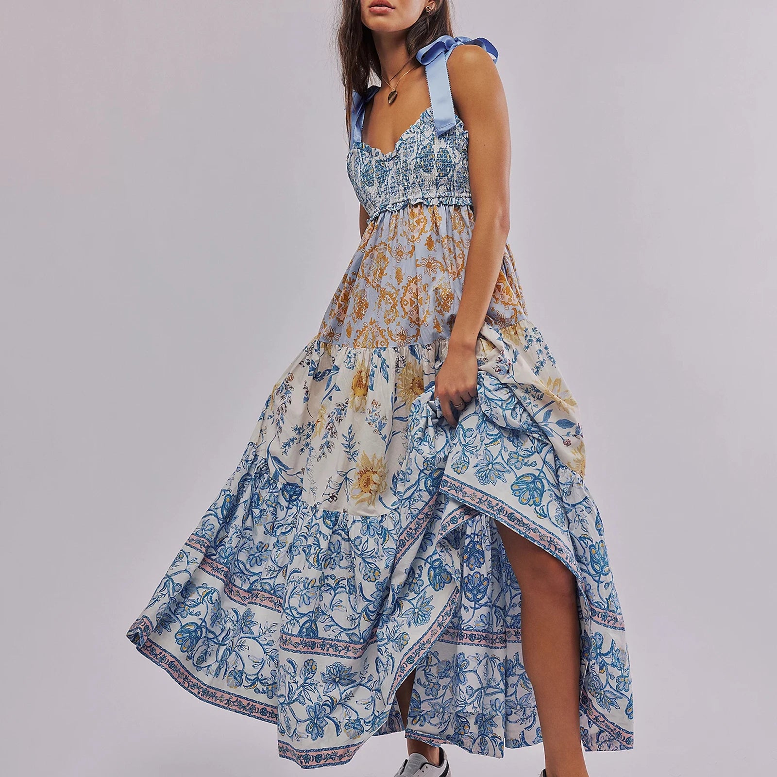 Woman wearing a floral dress with a blue and white pattern on a gray background