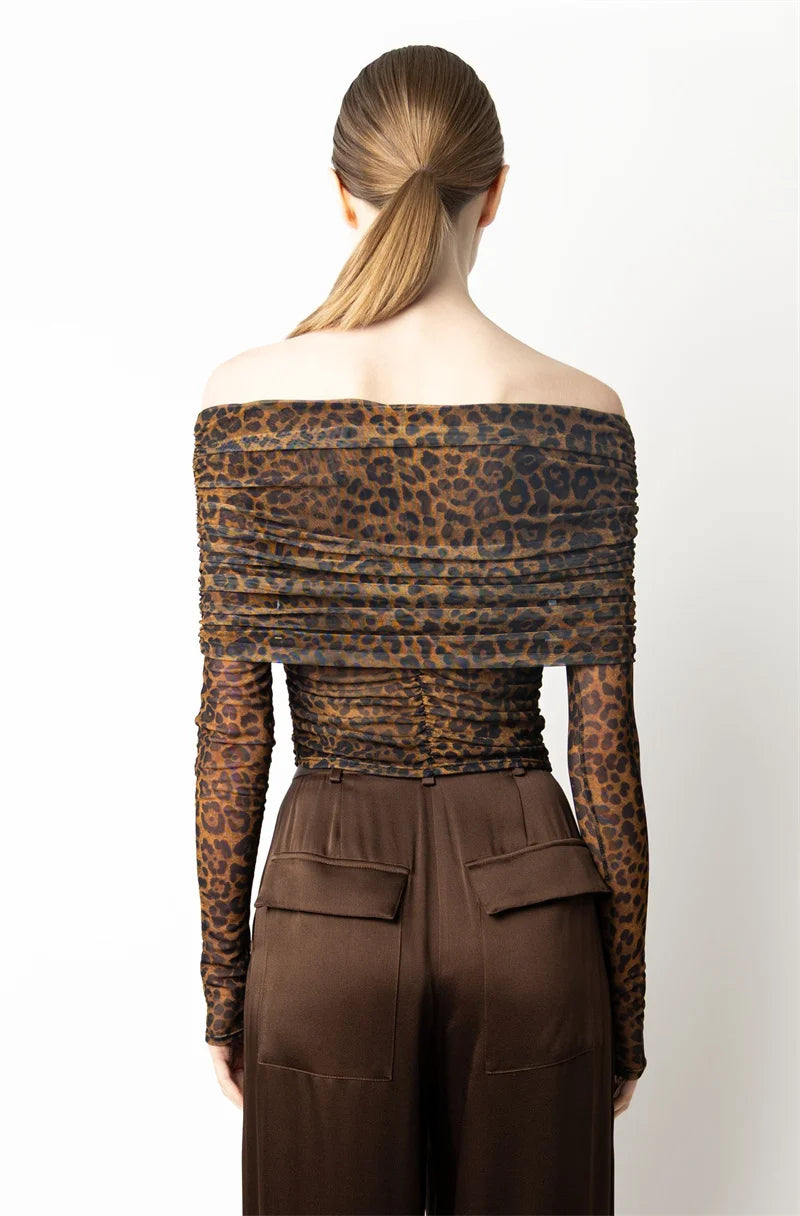 Person wearing a leopard print off-shoulder top and brown pants