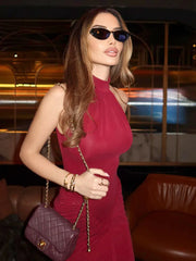 Woman in a red dress holding a purple handbag in an indoor setting