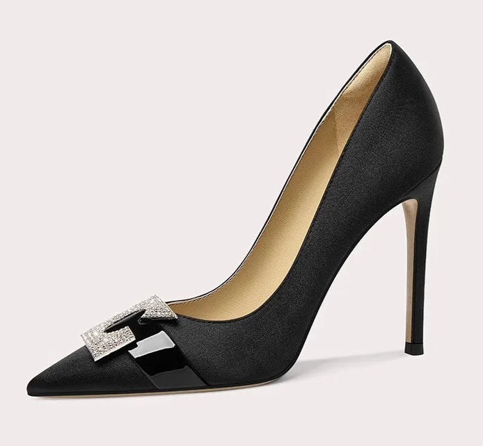 Black high-heeled shoe with a decorative bow on a light gray background