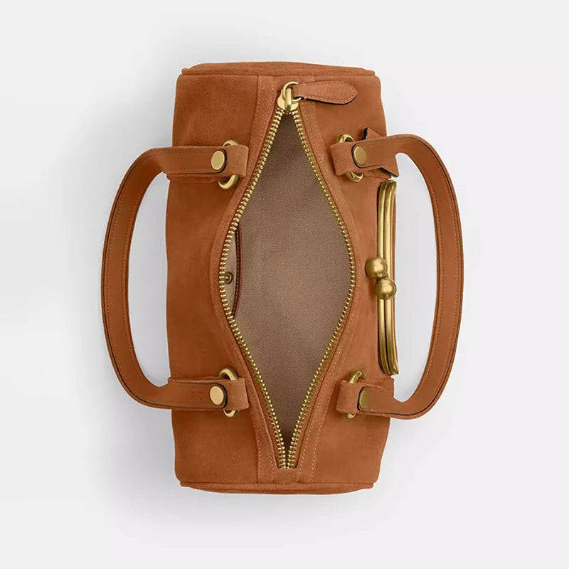 Brown leather handbag with gold zipper and handles on a light gray background