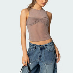 Woman wearing a brown sleeveless top and blue jeans on a light gray background