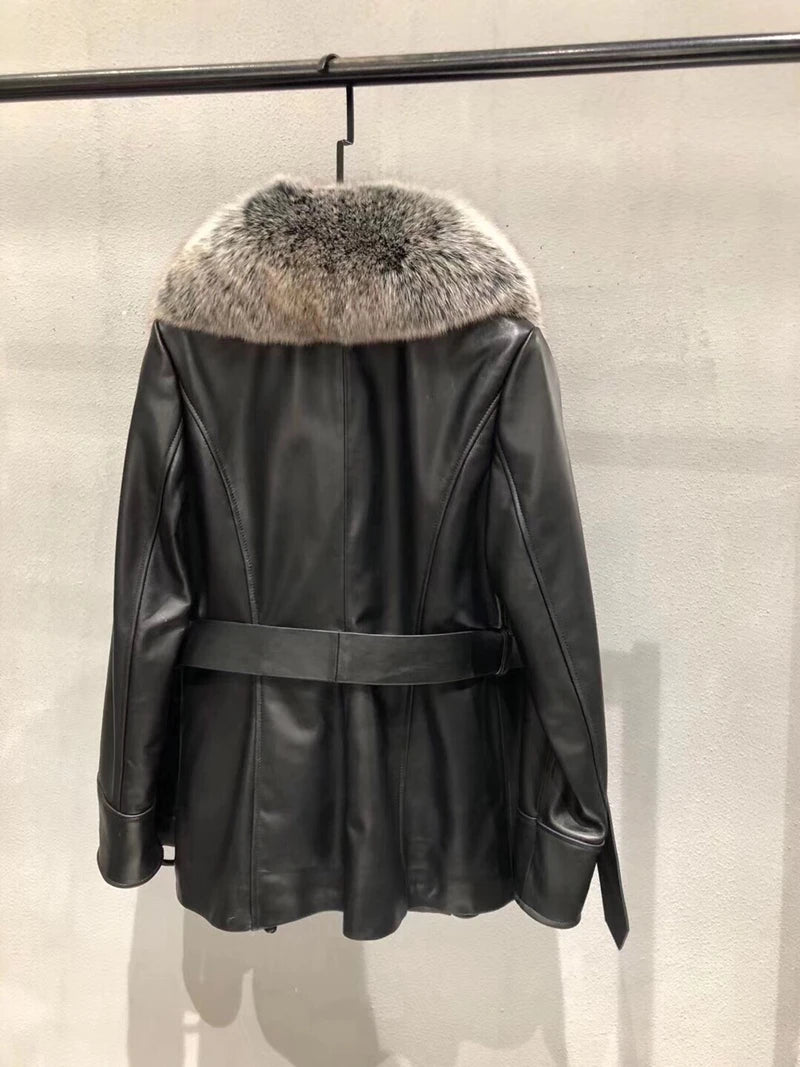 Black leather jacket with fur collar hanging on a rack against a neutral background