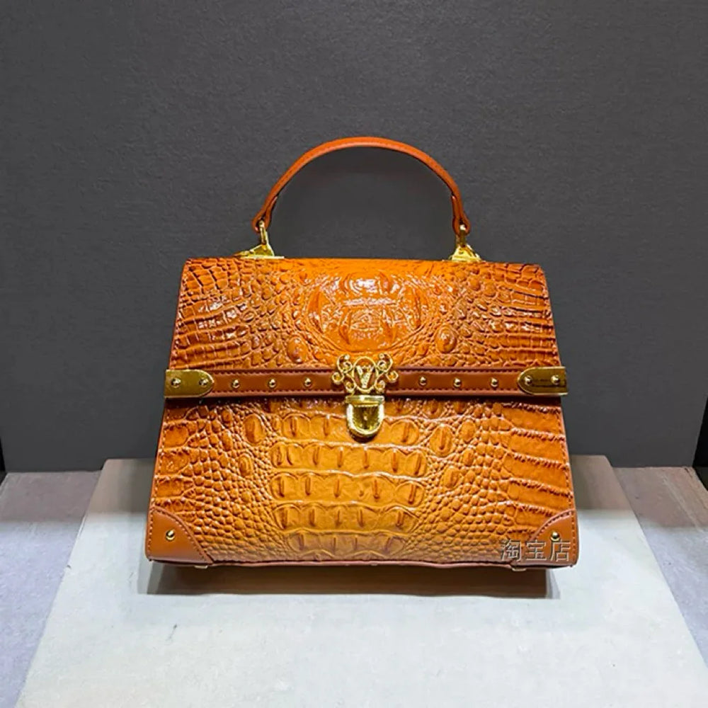 Structured crocodile embossed leather top handle bag in orange with gold hardware.