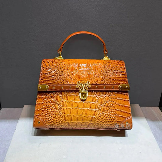 Structured crocodile embossed leather top handle bag in orange with gold hardware.