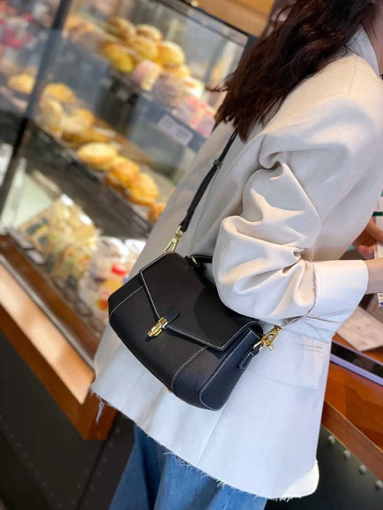 Person holding a black handbag in front of a bakery display
