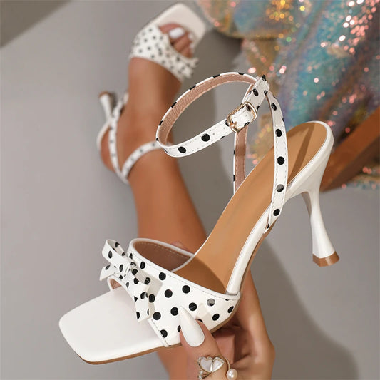 Close-up of white polka dot stiletto heels with bow