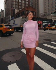 Woman in a pink dress standing on a city street with buildings and taxis in the background