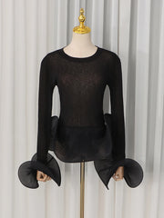 Black sheer knit top with voluminous pleated flare sleeves and ruffled hem