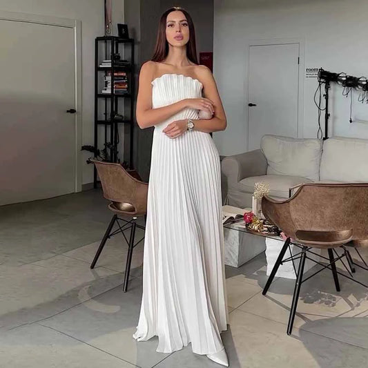 Woman in a white strapless dress standing in a modern living room.