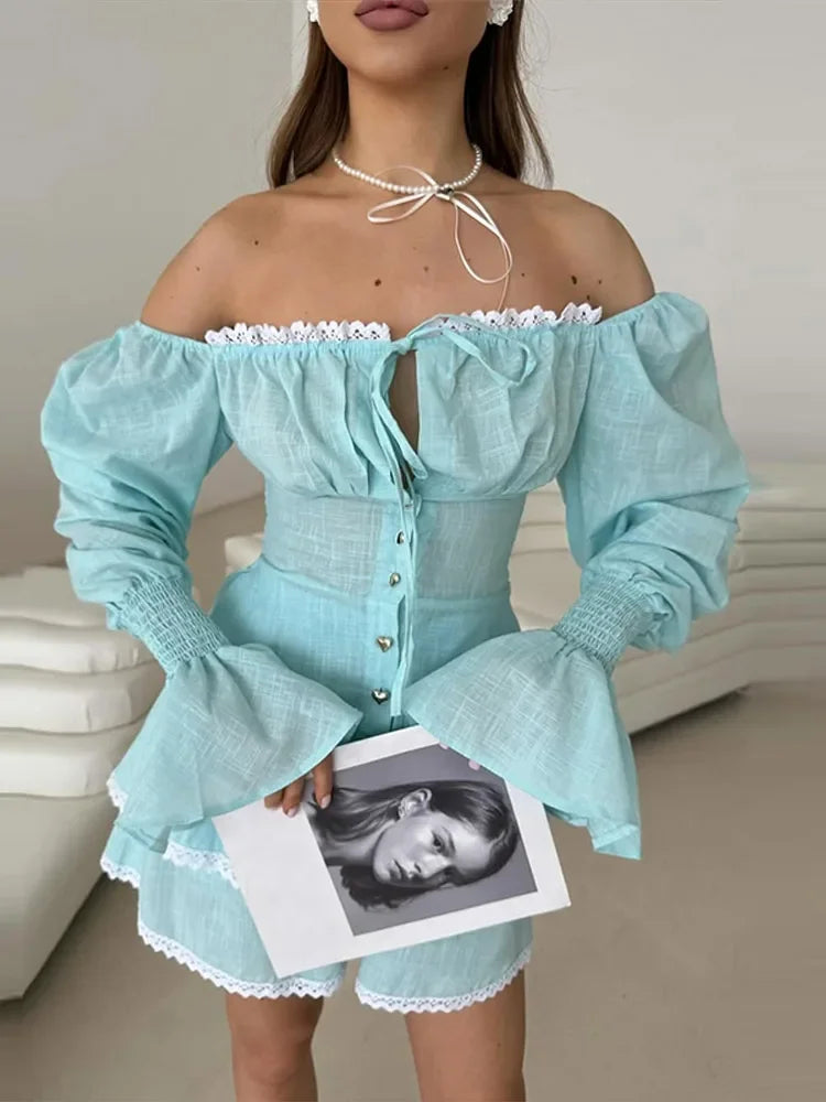 Woman wearing a light blue off-shoulder dress with long sleeves, holding a magazine.