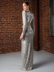 Woman wearing a silver sequin dress against a brick wall.