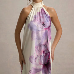 Woman wearing a floral halter neck dress on a plain background