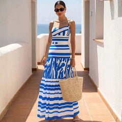 Woman wearing a blue and white striped bandage bodysuit and tiered maxi skirt on a balcony overlooking the ocean.