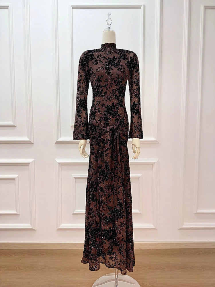 Long-sleeve dress with floral pattern on a mannequin against a white paneled wall.