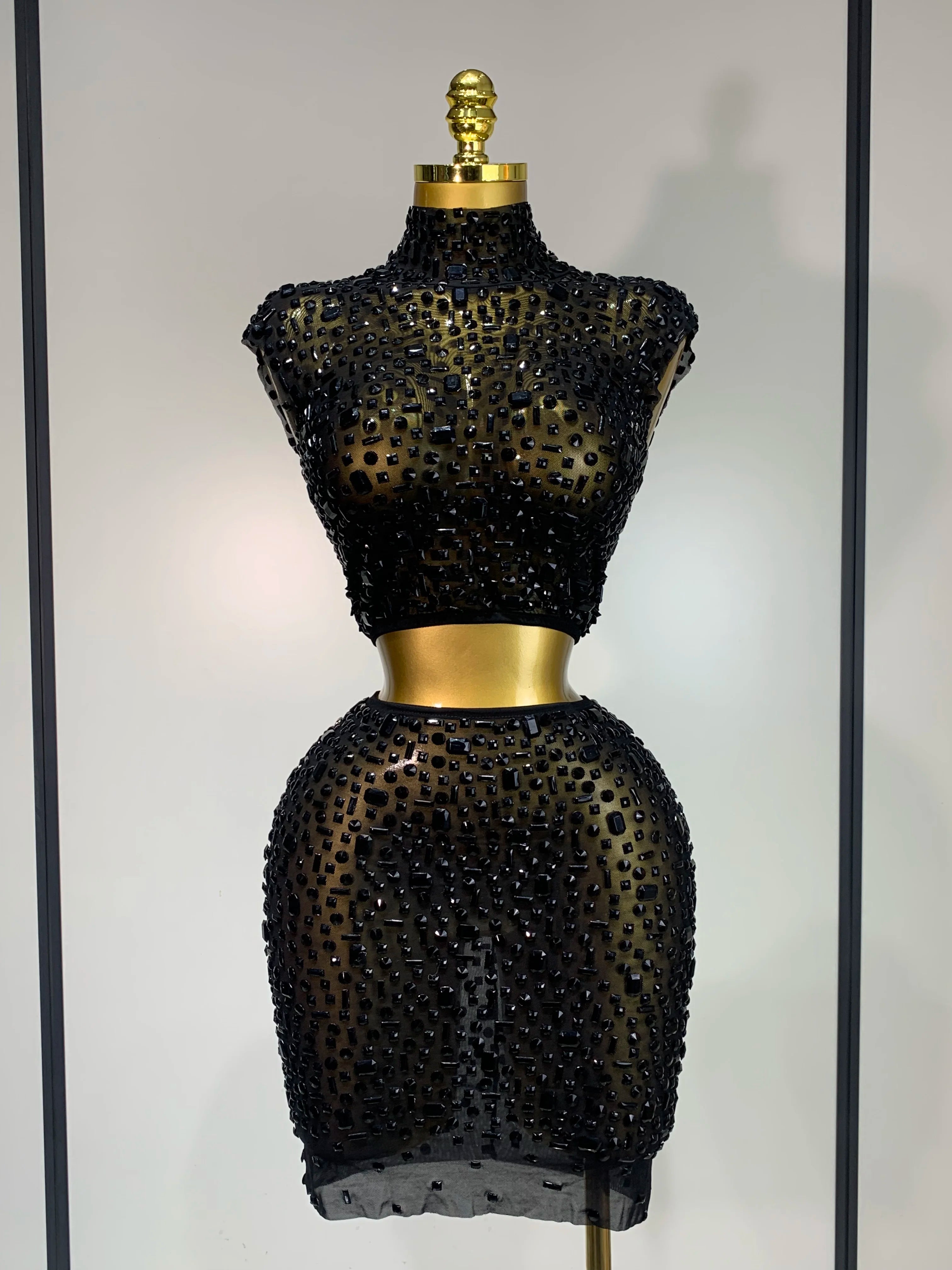 Black beaded dress on a mannequin against a neutral background