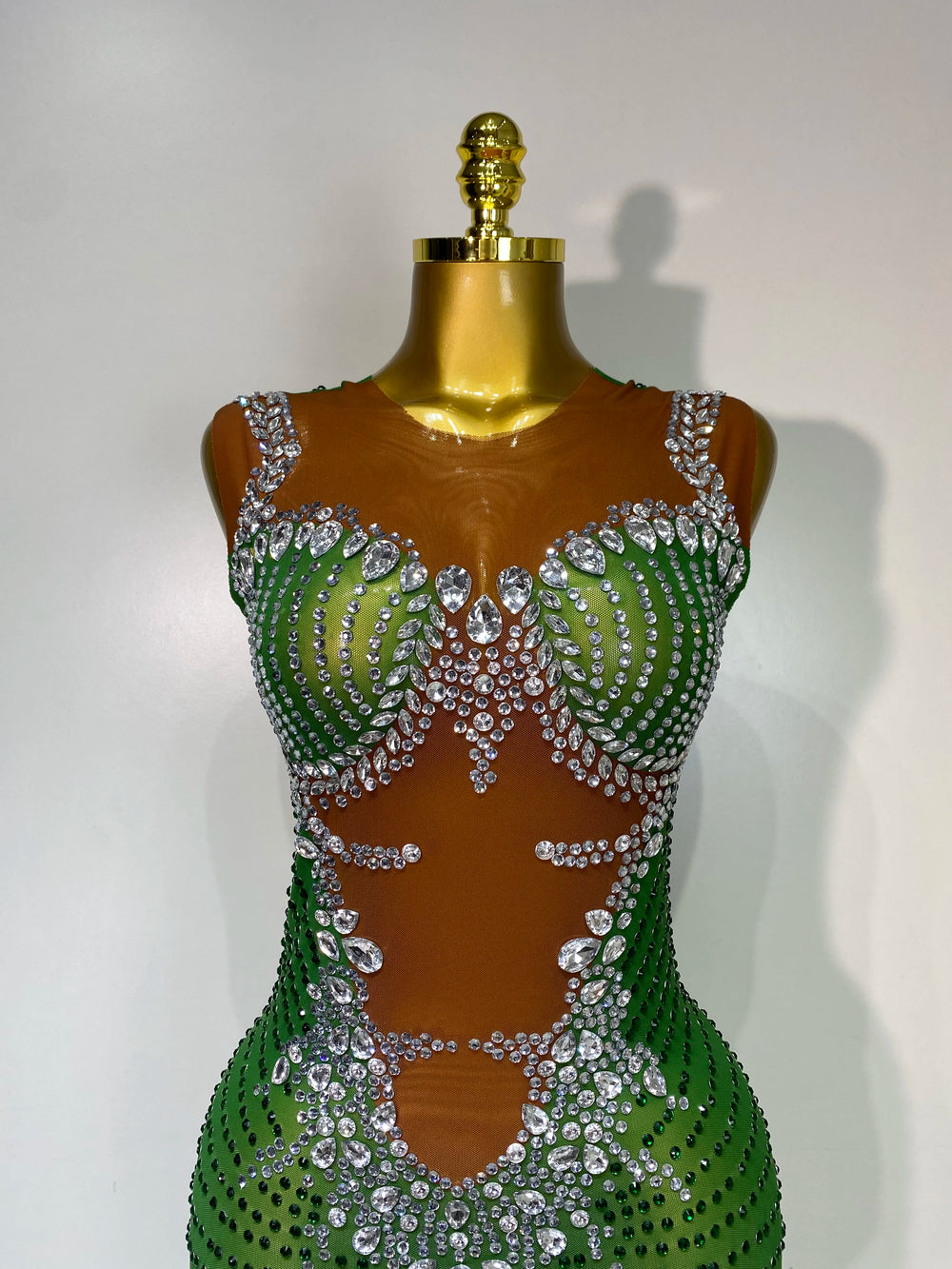 Green and silver beaded dress on a mannequin against a white background