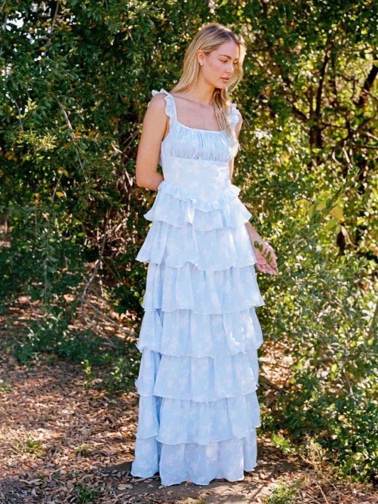 Woman in a light blue ruffled dress standing in a forest setting