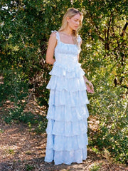 Woman in a light blue ruffled dress standing in a forest setting