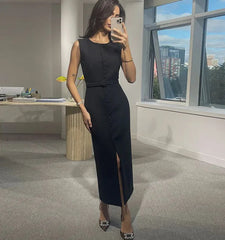 Woman taking a mirror selfie in a black dress in an office setting with large windows.