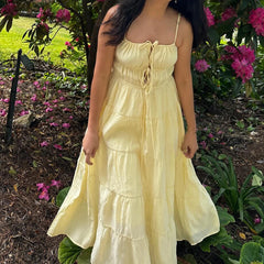 Person wearing a yellow dress standing in a garden with pink flowers.