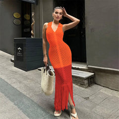 Woman in an orange and red dress standing on a sidewalk.